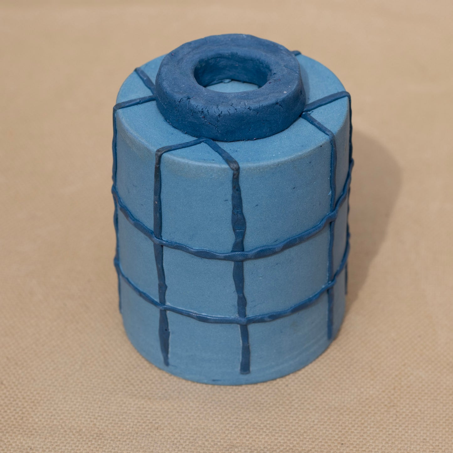 The foot of a handmade blue cup with a grid pattern
