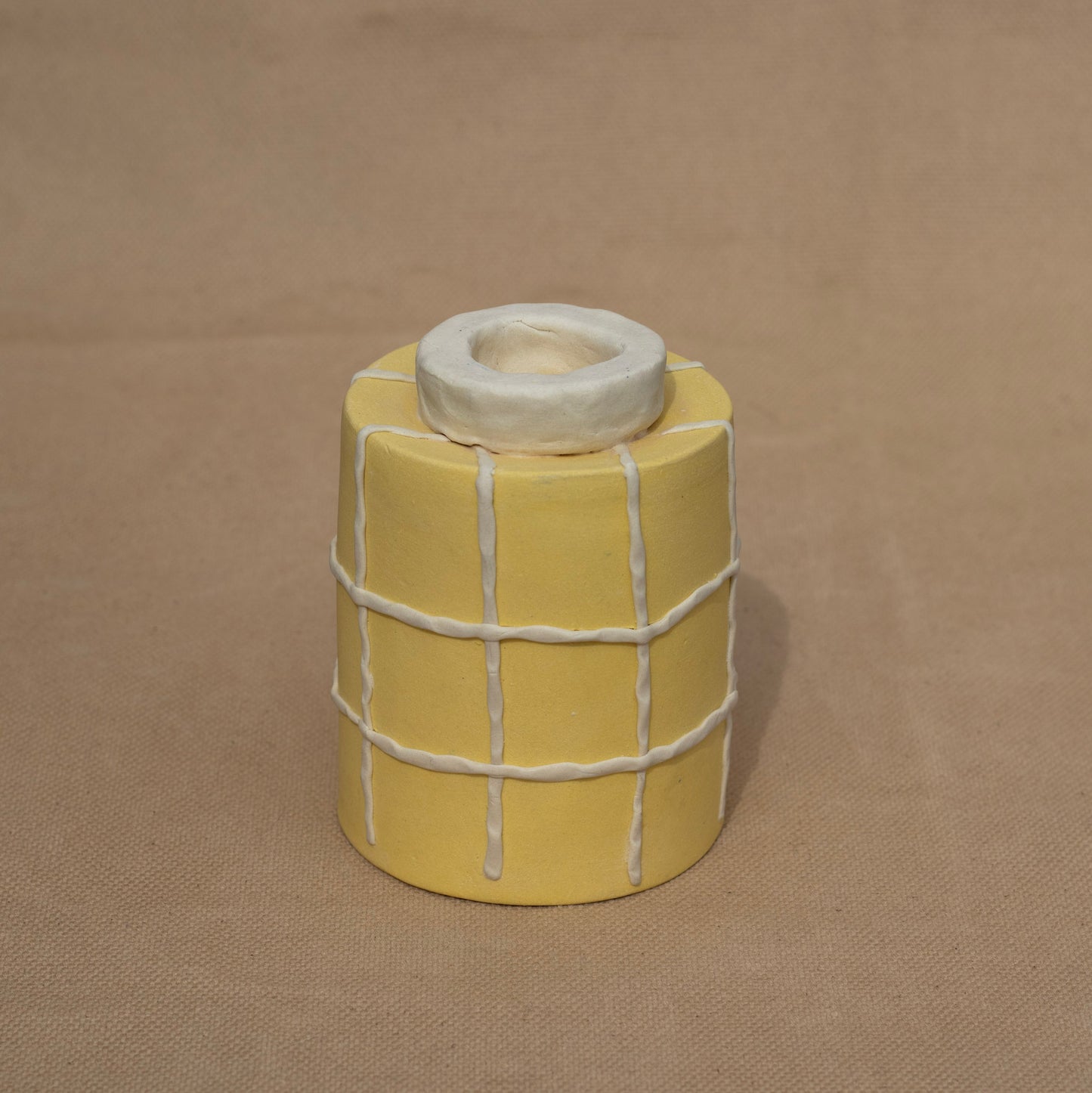 The foot of a handmade yellow cup with a grid decoration
