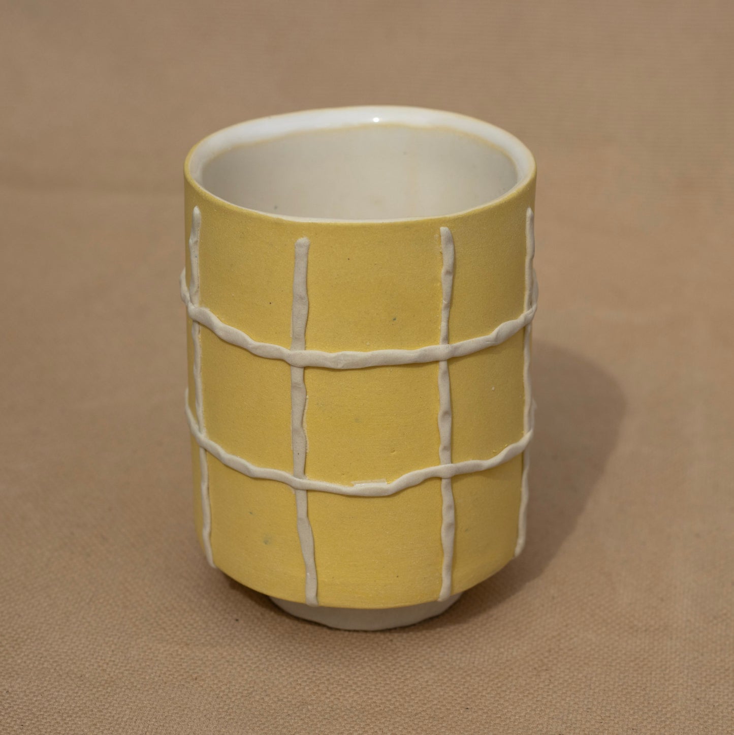 Handmade yellow cup with a white grid