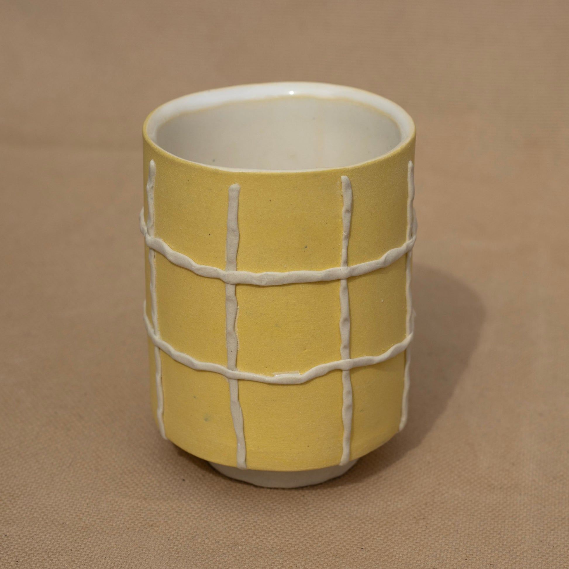 Handmade yellow cup with a white grid